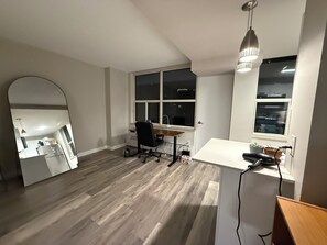 A room with a desk, chair, large windows, and a mirror.
