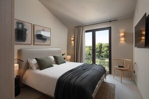 Ein modernes Schlafzimmer mit einem großen Bett, einem Sessel und einem an der Wand befestigten Fernseher.