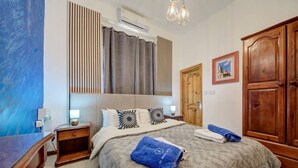 Ein Schlafzimmer mit Bett, Nachttischen, einem Kleiderschrank, einem Gemälde und einem Fenster mit Jalousien.