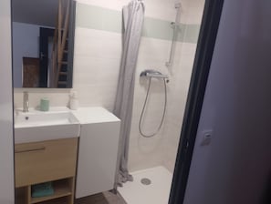 Une salle de bain équipée d’une douche, d’un lavabo, d’un miroir et d’un porte-serviettes.