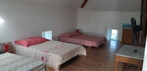 Un dormitorio con dos camas, piso de madera, una mesita y un aparador.