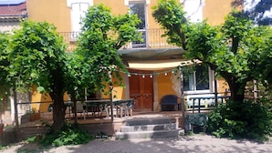 A courtyard with outdoor seating, a staircase leading to a building entrance, and a string of lights.