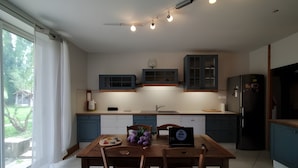 A modern kitchen with a dining table, chairs, a refrigerator, and cabinets.