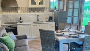 Una cucina moderna con mobili bianchi, forno integrato e zona pranzo con sedie in vimini e tavolo apparecchiato per due.