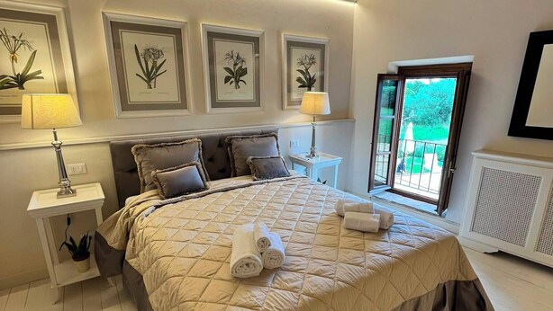 Una camera da letto con un letto grande, due comodini, una finestra con vista e stampe botaniche incorniciate alle pareti.