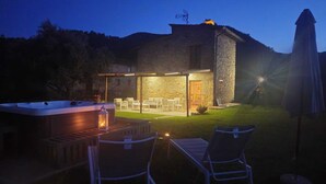 Un edificio in pietra con patio coperto, posti a sedere all'aperto e una vasca idromassaggio.