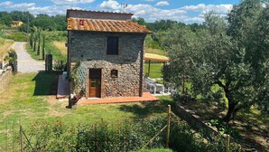 Una casa in pietra con tetto in tegole, una porta di legno e un piccolo portico.