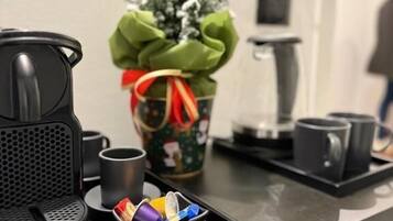 En kaffebryggare, en mugg, ett litet bricka med färgglada koppar och en julgran med ett grönt band.