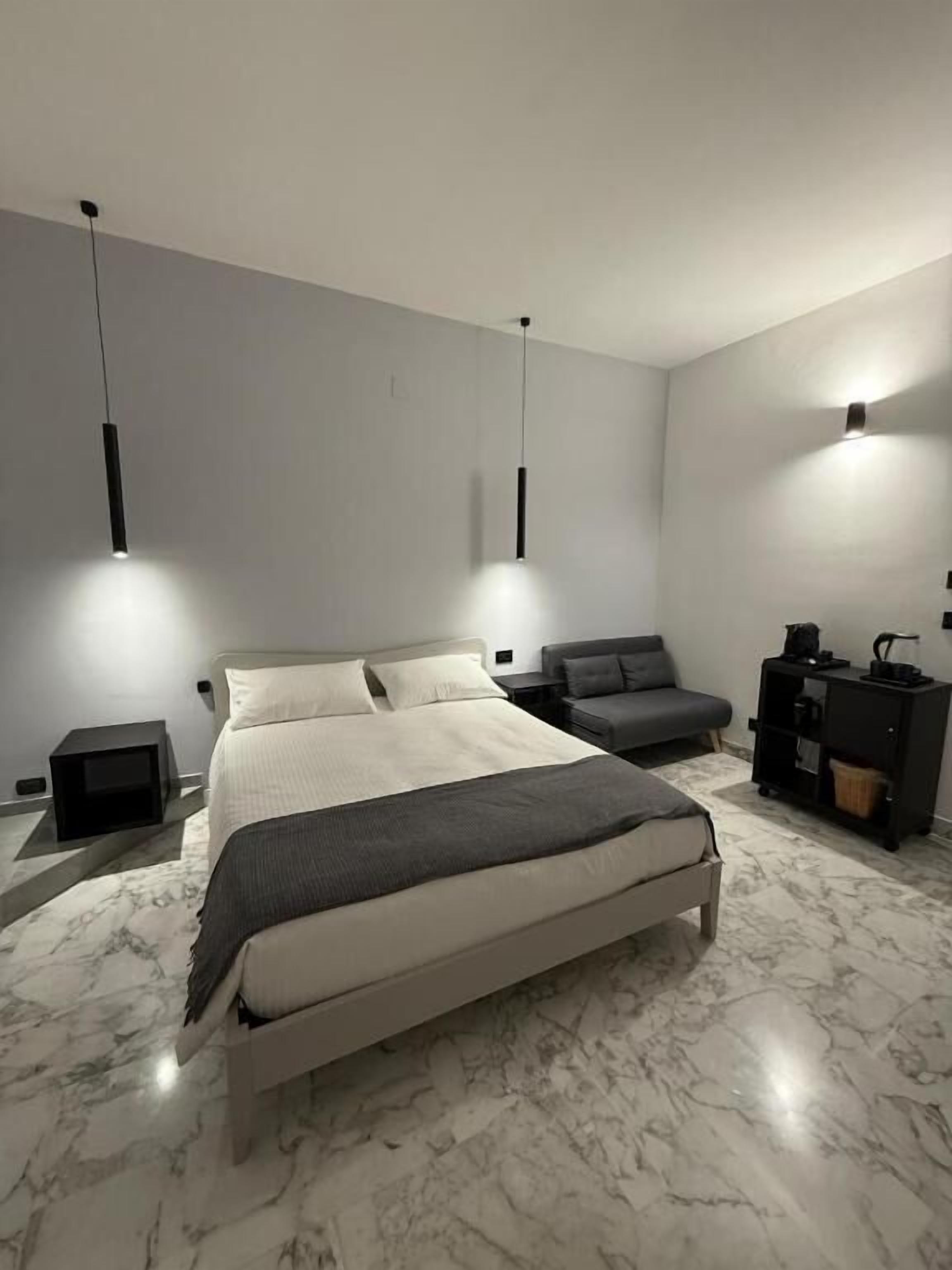 Un dormitorio moderno con una cama grande, dos mesitas de noche, un tocador y lámparas colgantes.