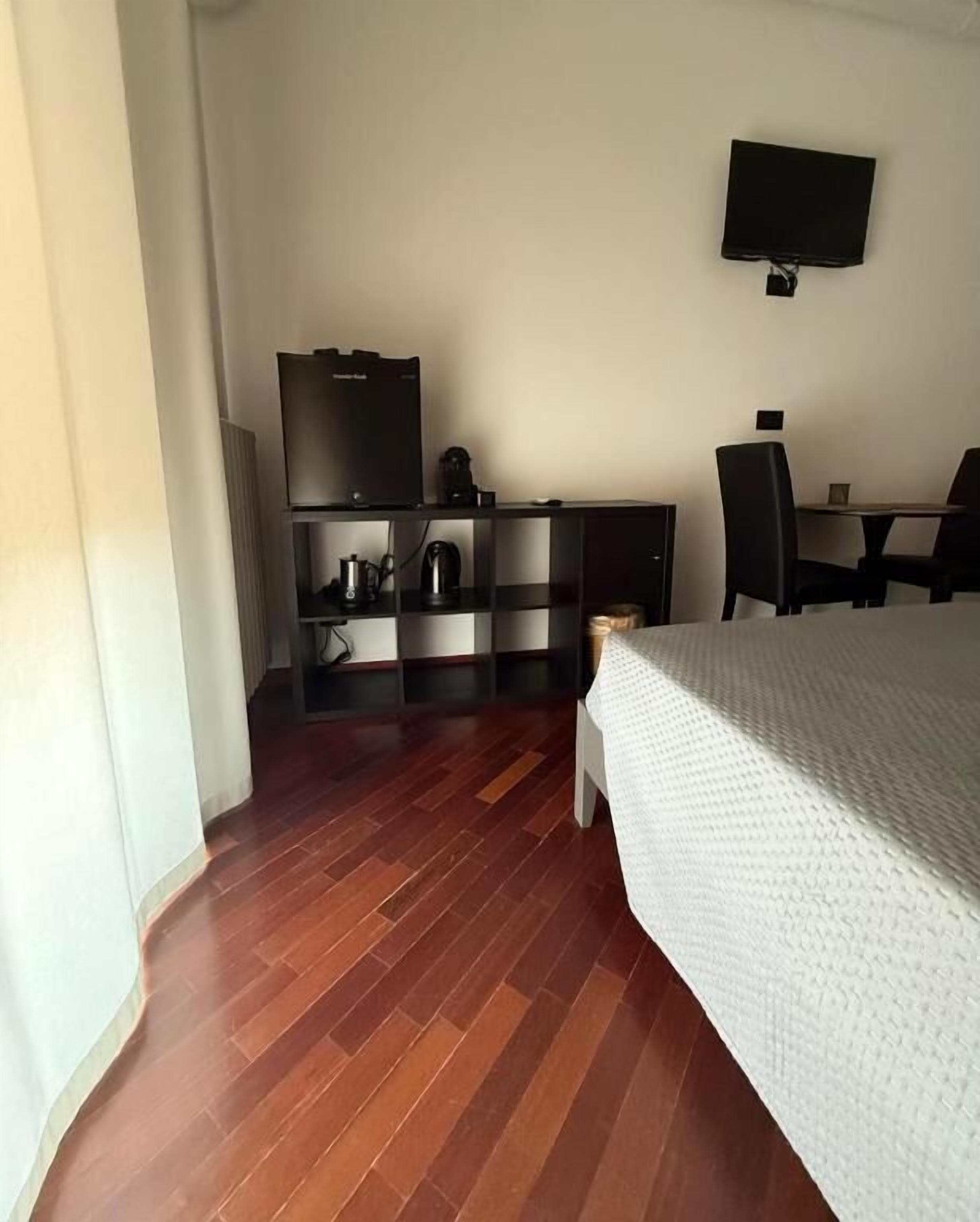 A hotel room with a bed, a desk, a chair, a television, and a minibar.
