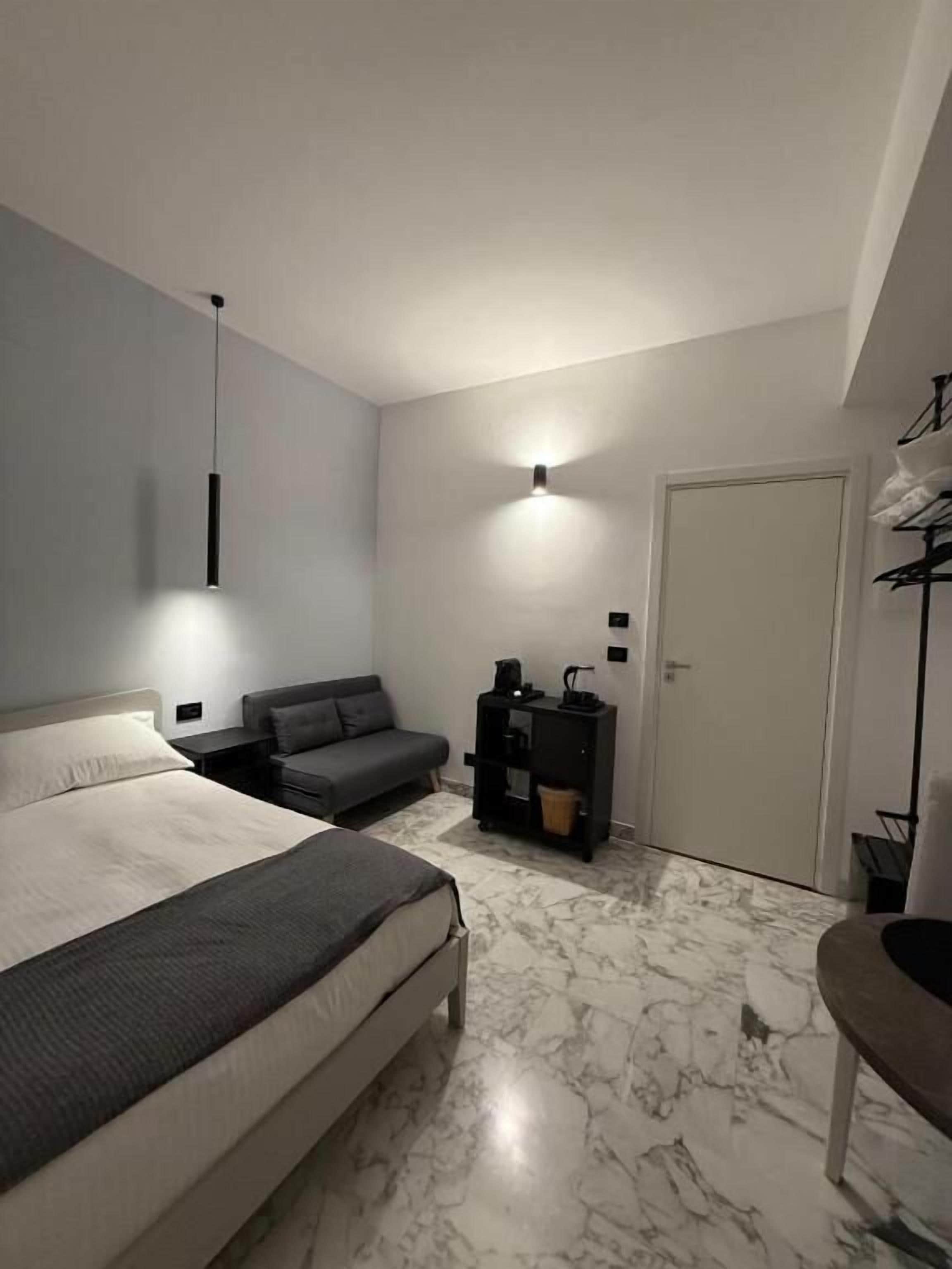 A bedroom with a bed, a sofa, a desk, and a wardrobe.