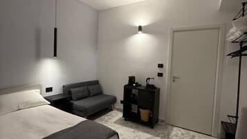 A bedroom with a bed, a sofa, a desk, and a wardrobe.