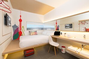 A modern hotel room with a bed, a desk, a laptop, a chair, a bathroom with a mirror, and a window with a cityscape view. - Yaas Hôtel Dakar République (Dakar)