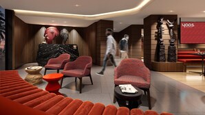 A modern hotel lobby with seating areas, a reception desk, and a wall-mounted sculpture.