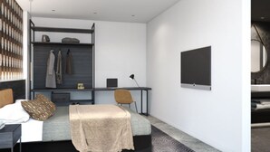 Ein modernes Schlafzimmer mit einem Bett, einem Schreibtisch und einem Stuhl. Ein Kleiderschrank mit Kleidung ist vorhanden, sowie ein Flachbildfernseher an der Wand.