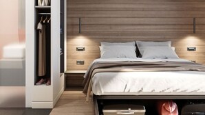 Ein modernes Schlafzimmer mit einem hölzernen Kopfteil, einem eingebauten Kleiderschrank, Nachttischen und einem Bett mit weißer Bettdecke.