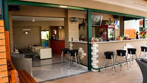 A bar area with stools, a counter, and a television screen. - Nikos Villas - Garden & Pool View Gem in Kavos (Kavos)