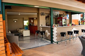 A bar area with stools, a counter, and a television screen.