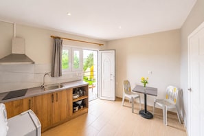 A modern kitchen with a built-in stove, a sink, and wooden cabinets. There is a dining area with a table and chairs.