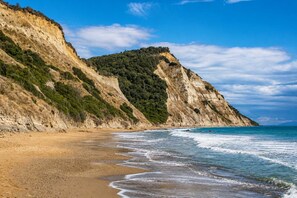 A coastal beach with a sandy shore and a steep cliff.