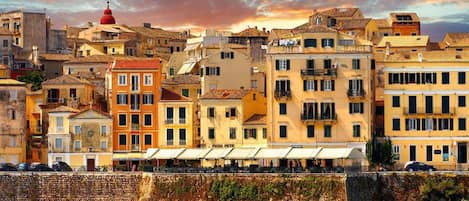 A coastal cityscape with historic buildings, a prominent red dome, and a stone wall overlooking the sea.