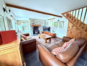 Ein Wohnzimmer mit Kamin aus Stein, einer Ledersofa, einem Holztisch und einem Fernseher.