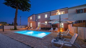A swimming pool with lounge chairs and umbrellas, a stone patio, and a two-story building with windows and air conditioning units. - Holiday Home with Private Pool, Istria (Up to 10 Guests, Pet Friendly) (Smoljanci)