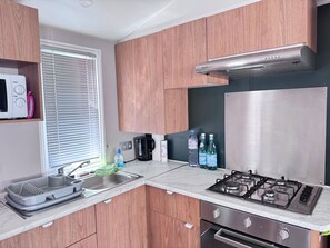 Eine moderne Küche mit Holzausstattung, einem Edelstahlherd, einer Mikrowelle und einer Kaffeemaschine.