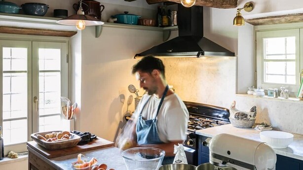A kitchen with a large island, a stove, and a mixer.