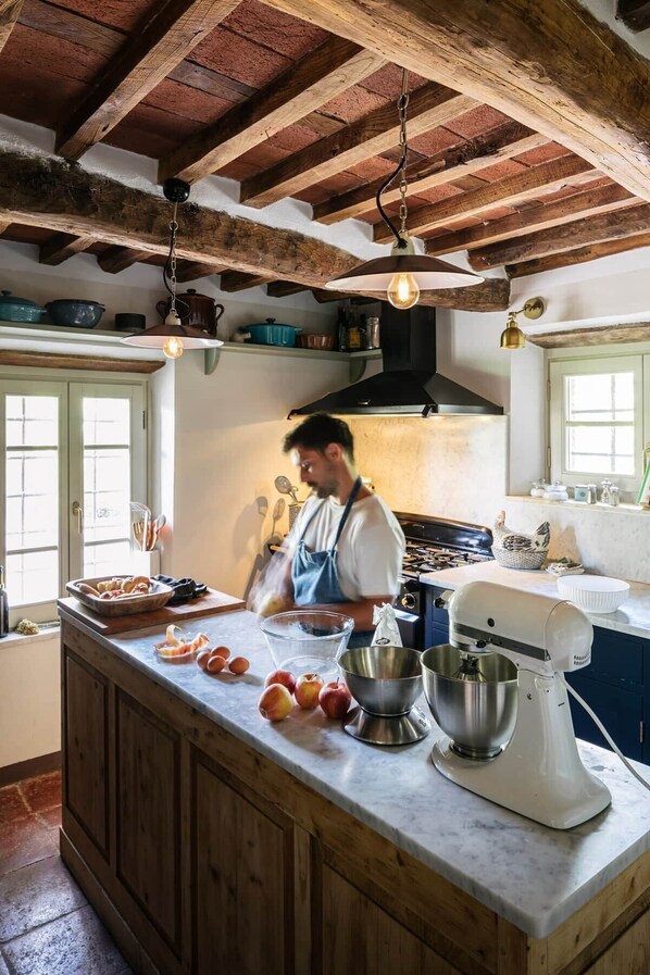 A kitchen with a large island, a stove, and a mixer.