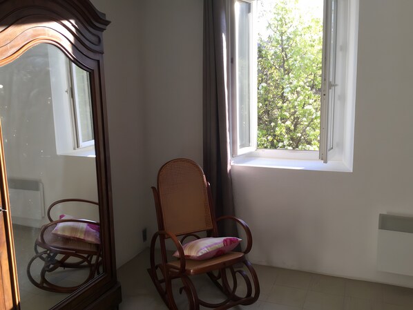 A room with a wooden rocking chair, a large mirror, and a window with a view of trees. - Cottage near Chauvet Cave and the Ardèche Gorges (Gras)