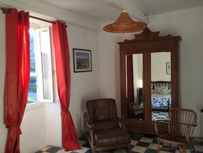 A room with a checkered floor, a brown leather chair, a wooden chair, a large mirror, and red curtains. - Cottage near Chauvet Cave and the Ardèche Gorges (Gras)