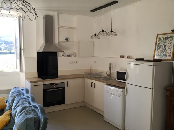Eine moderne Küche mit weißen Schränken, einem eingebauten Backofen, einer Spülmaschine, einer Mikrowelle und Pendelleuchten.