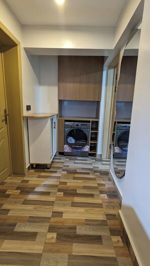 A laundry room with two washing machines, a small refrigerator, and a wooden cabinet. - Cozy One bedroom apartment in Kigali , Rebero with panoramic mountain views (Kigali)