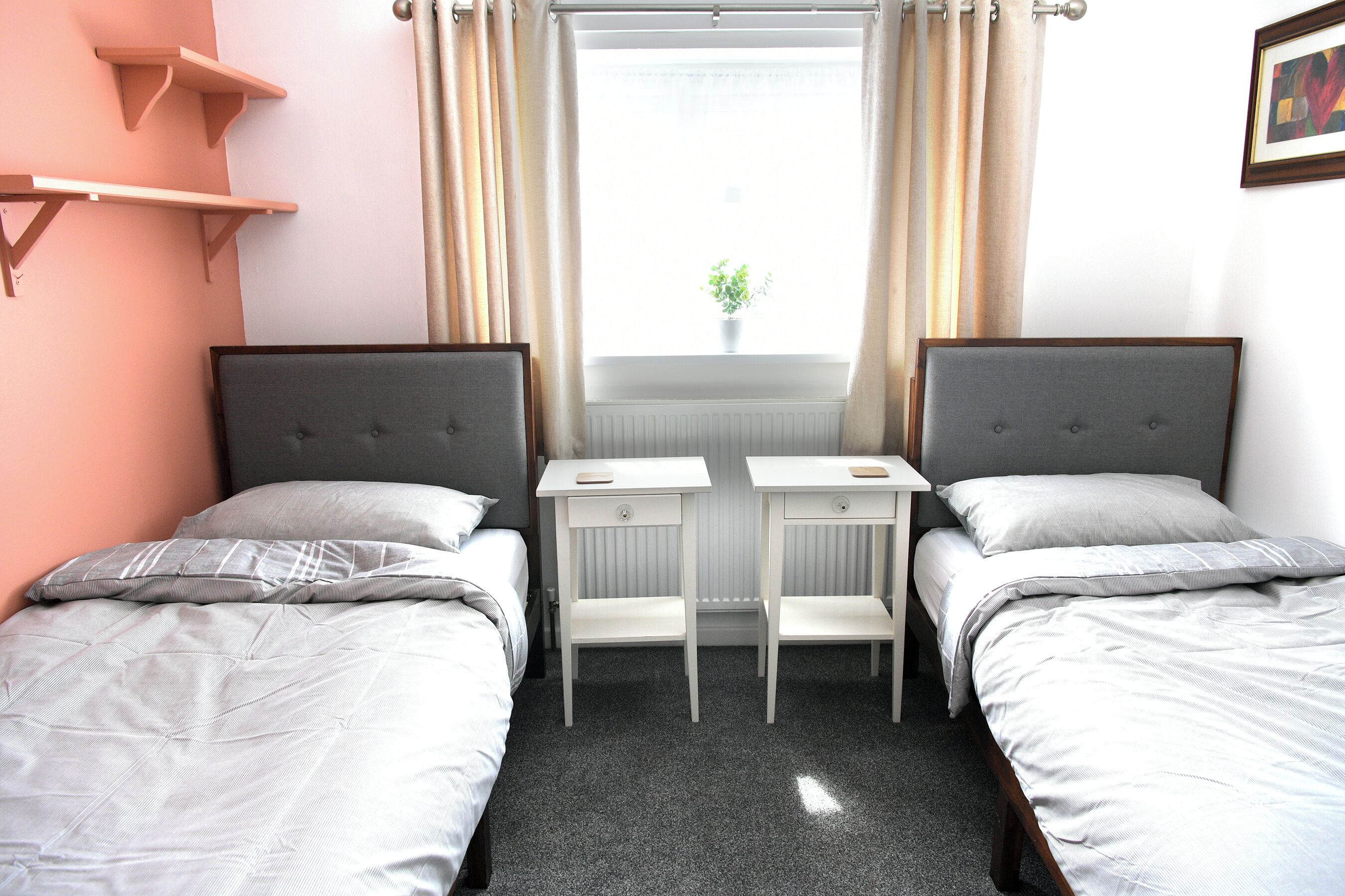 Habitación doble con dos camas, una mesita y una ventana con cortinas.