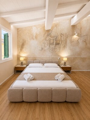 Un dormitorio amplio y moderno con una cama grande, pisos de madera y un mural en la pared.