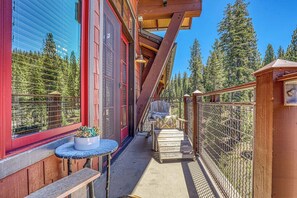 Un bâtiment en bois doté d’un balcon, d’une plante en pot et d’une chaise.