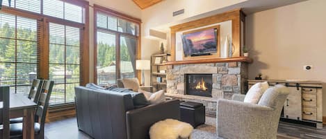 A living room with a fireplace, a sofa, a chair, and a dining area.