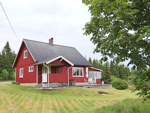 A red house with a sloped roof, a porch, and a window overlooking a grassy area. - 4 Star Holiday Home in Knared (Knared)