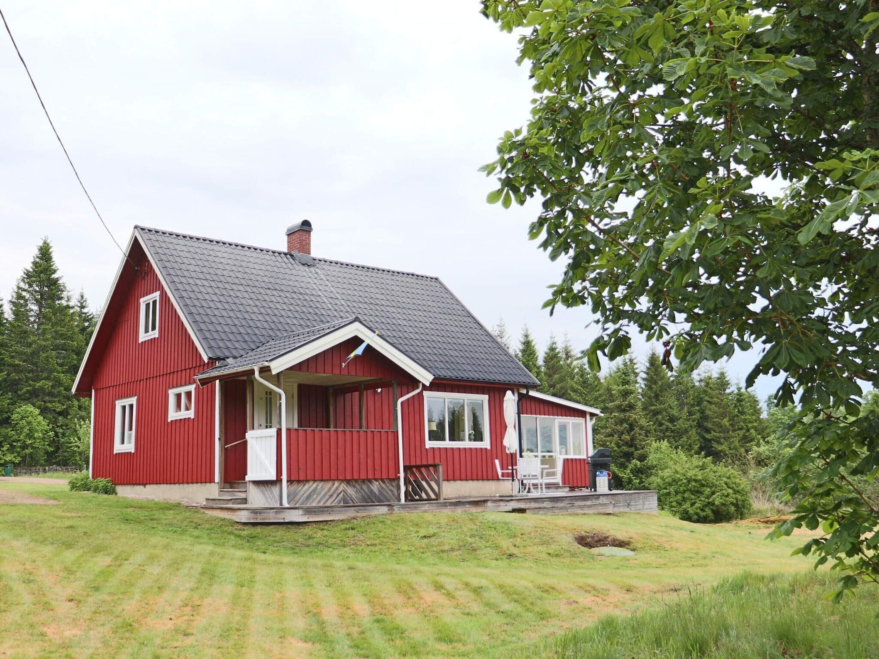 A red house with a sloped roof, a porch, and a small deck.