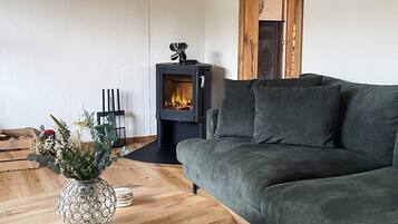 Ein modernes Wohnzimmer mit einer Couch, einer Zierdeovase, Holzboden und Kaminofen.