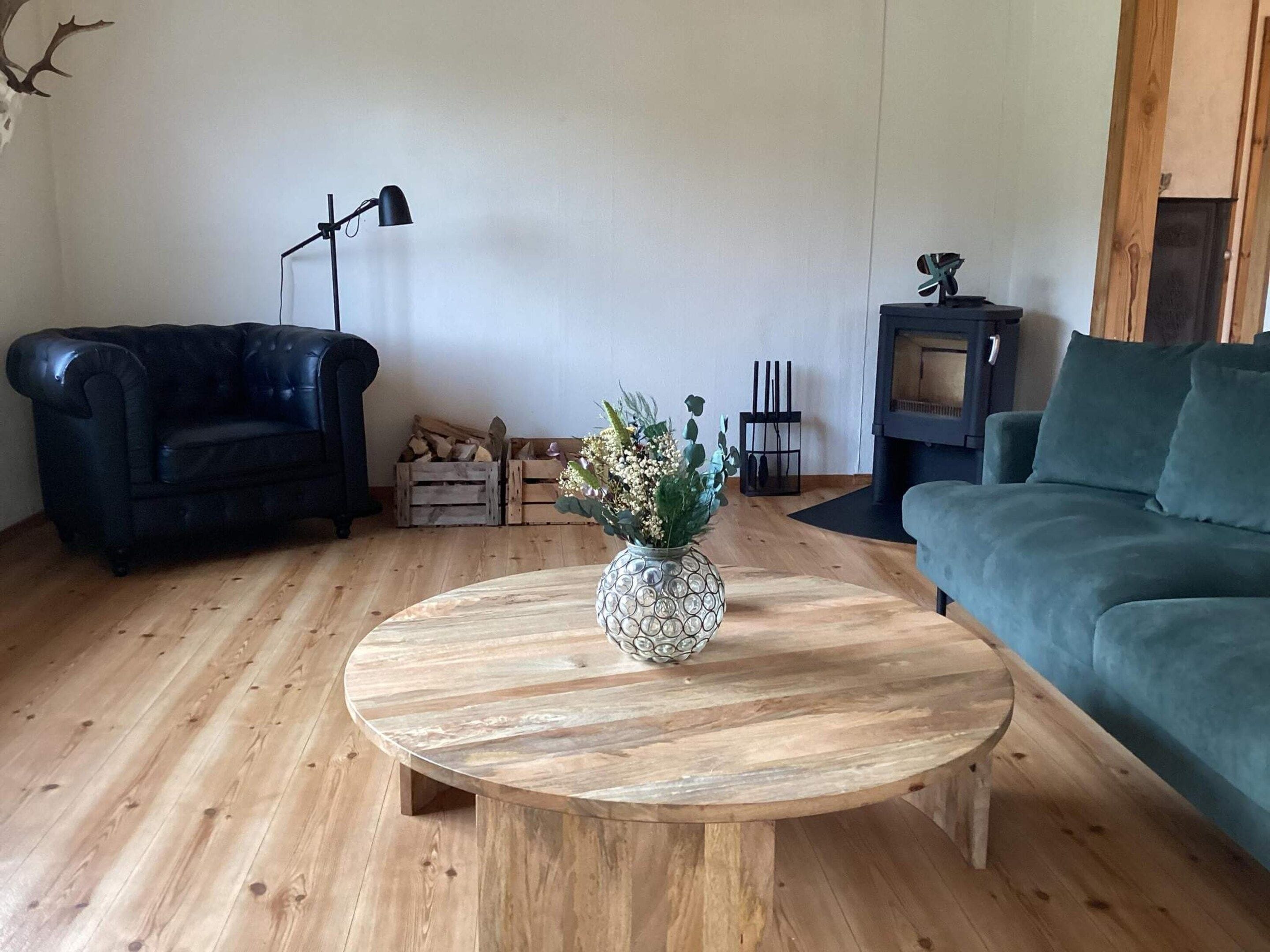 A living room with a round wooden coffee table, two sofas, a lamp, and a fireplace.