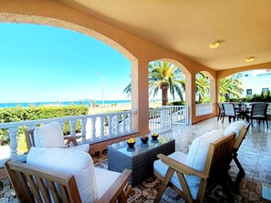 Un espacio de estar al aire libre cubierto, con vistas a la playa y al océano.