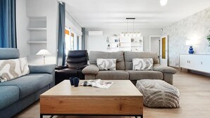 Una sala de estar moderna con sofá, sillón, mesa de centro y estantería.