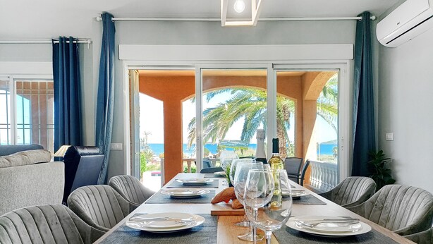 Un comedor con una mesa larga, sillas y vistas al mar.