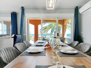 Un comedor con una mesa larga, sillas y vistas al mar.