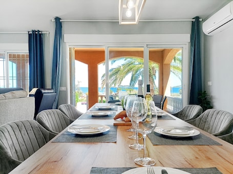 A dining area with a long table, chairs, and a view of the sea.. Apartment 'Villa with Pool and Bbq La Manga' with Sea View, Wi-Fi and Air Conditioning
