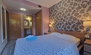 Ein Schlafzimmer mit einem Bett, einem Nachttisch, einer Wandlampe und einer Tür zu einem Badezimmer.