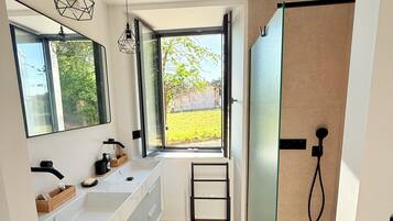 Een moderne badkamer met een groot raam, dubbele wastafels en een douchegedeelte.