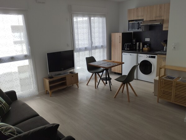 A modern living space with a sofa, TV, dining table, chairs, kitchen area, and laundry machine. - Recent 25m2 studio with parking space (Aytré)